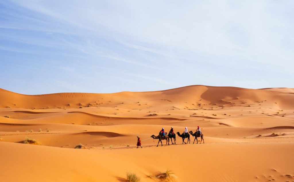 Turisti a dorso di cammello tra le dune di Merzouga, in Marocco, una popolare meta turistica nel Sahara.