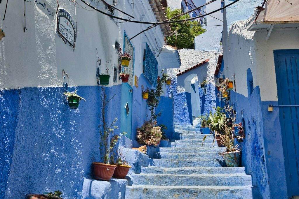 A narrow street with blue buildings and steps