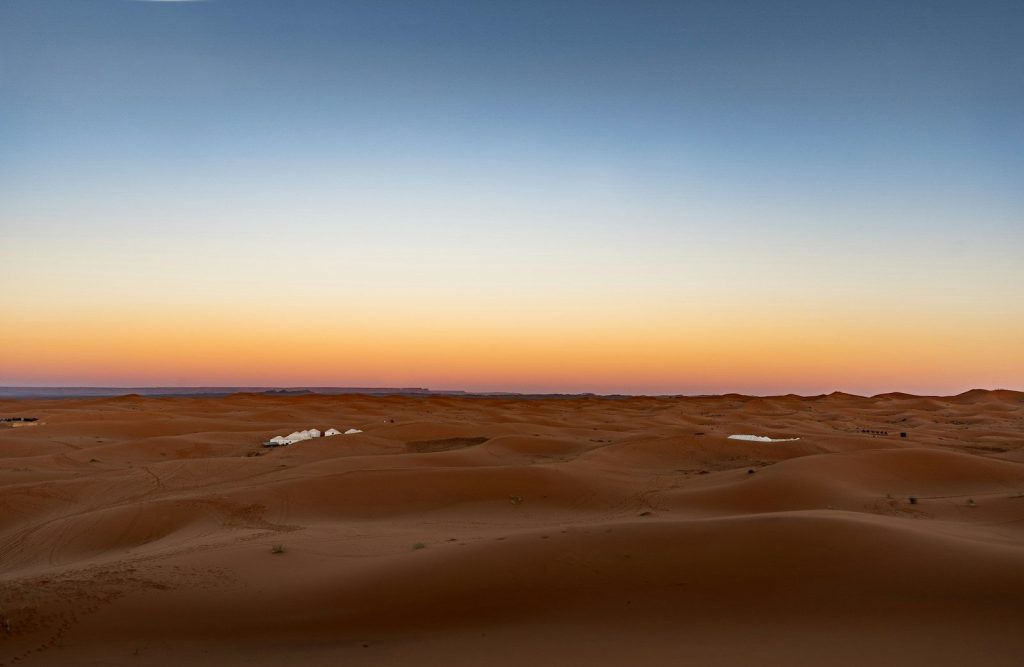 Dune di sabbia del deserto sotto un cielo sfumato al tramonto