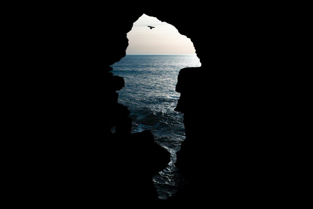 un uccello che vola sull'oceano da una grotta