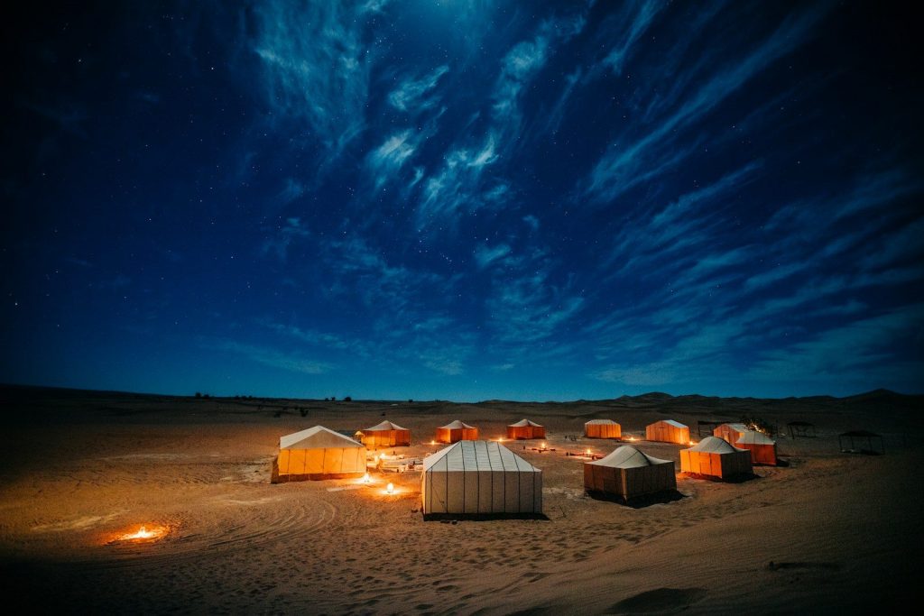 Tenda bianca e marrone su un campo marrone sotto un cielo blu durante la notte